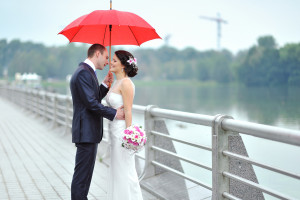 bride and groom under red umbrella